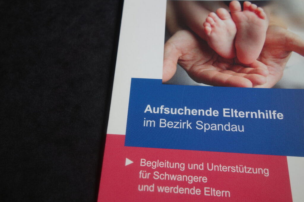 Ein Informationsflyer mit dem Titel &bdquo;Aufsuchende Elternarbeit im Bezirk Spandau&ldquo;, dazu ein Foto von Babyf&uuml;&szlig;en und Text f&uuml;r schwangere und werdende Eltern.